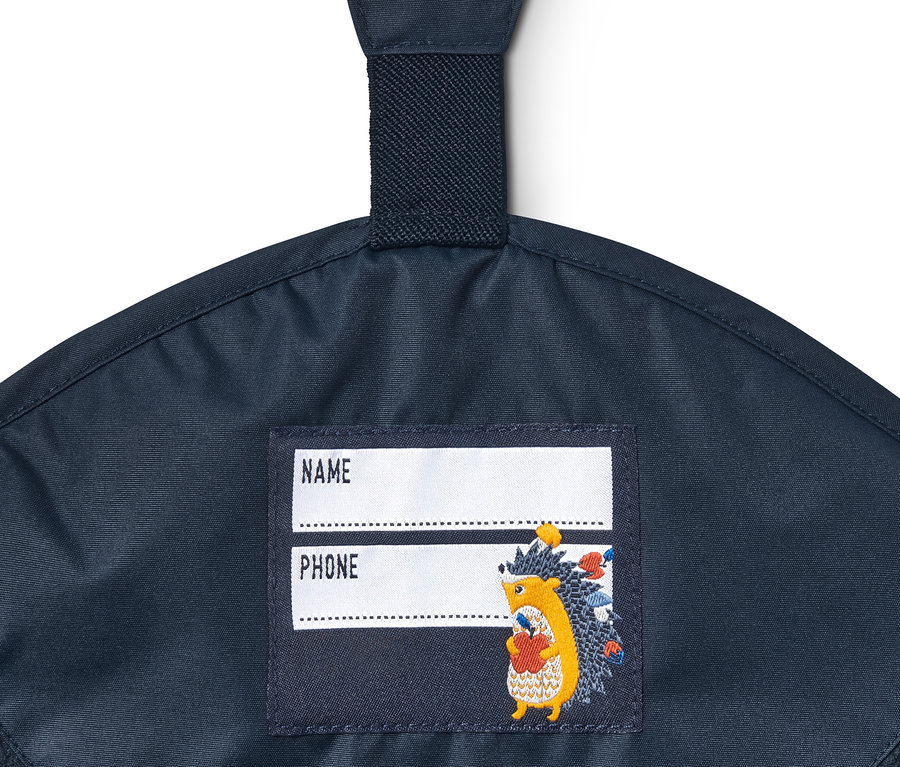 Detail der dunkelblauen Thermo-Regenhose aus recyceltem Material mit Namensschild und Igel-Applikation.