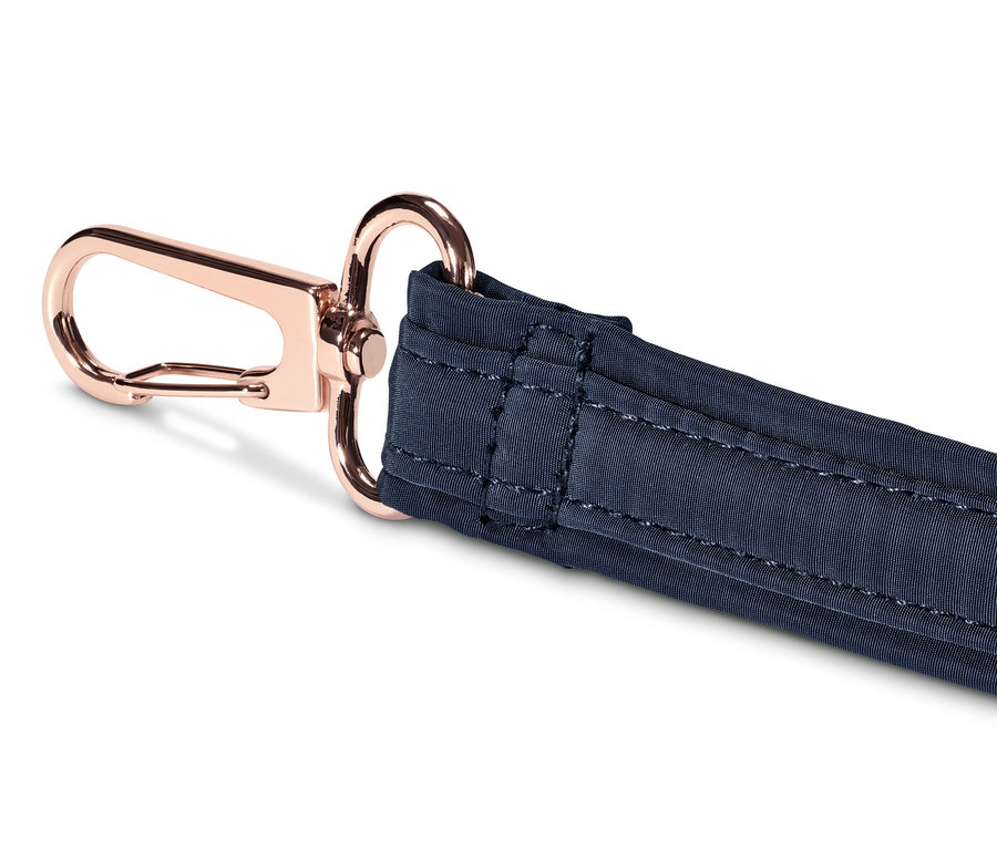 Detailaufnahme eines marineblauen Gurtes einer Sicherheits-Umhängetasche mit roségoldenem Karabiner.