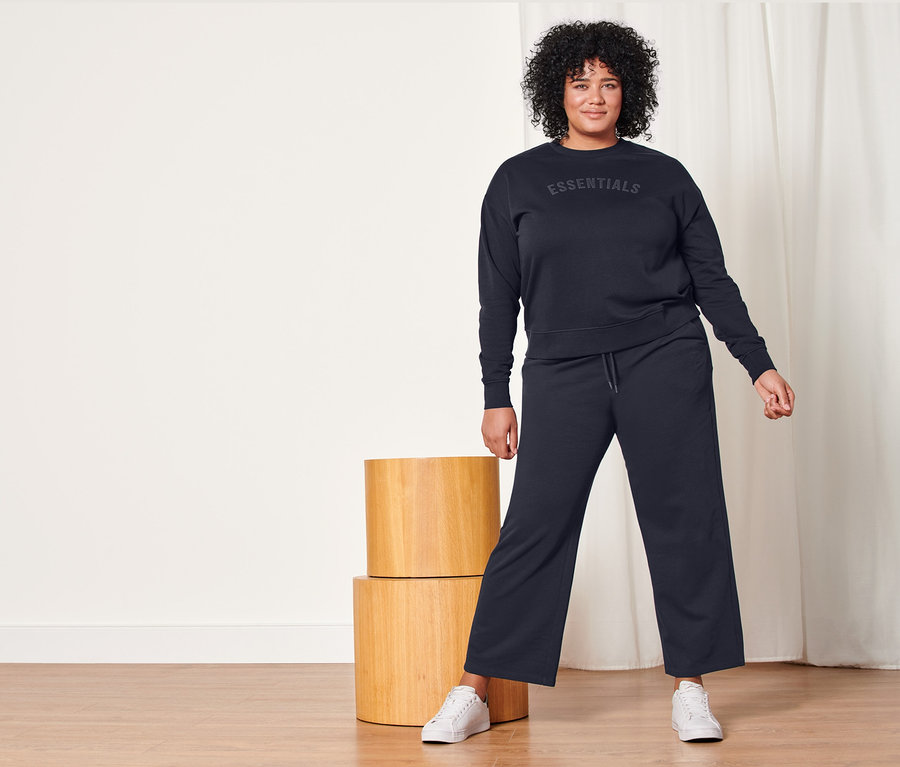 Frau posiert in dunkelblauen Sweatpants und Sweatshirt.