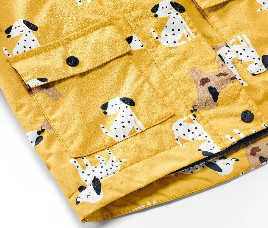Detailansicht einer gelben Kinder-Thermo-Regenjacke mit Dalmatiner-Print und Wassertropfen.