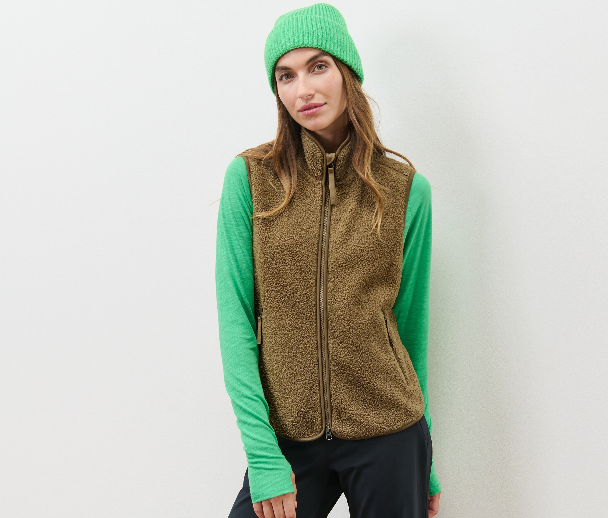 Frau trägt eine Teddy-Weste, ein grünes Oberteil und eine grüne Mütze.