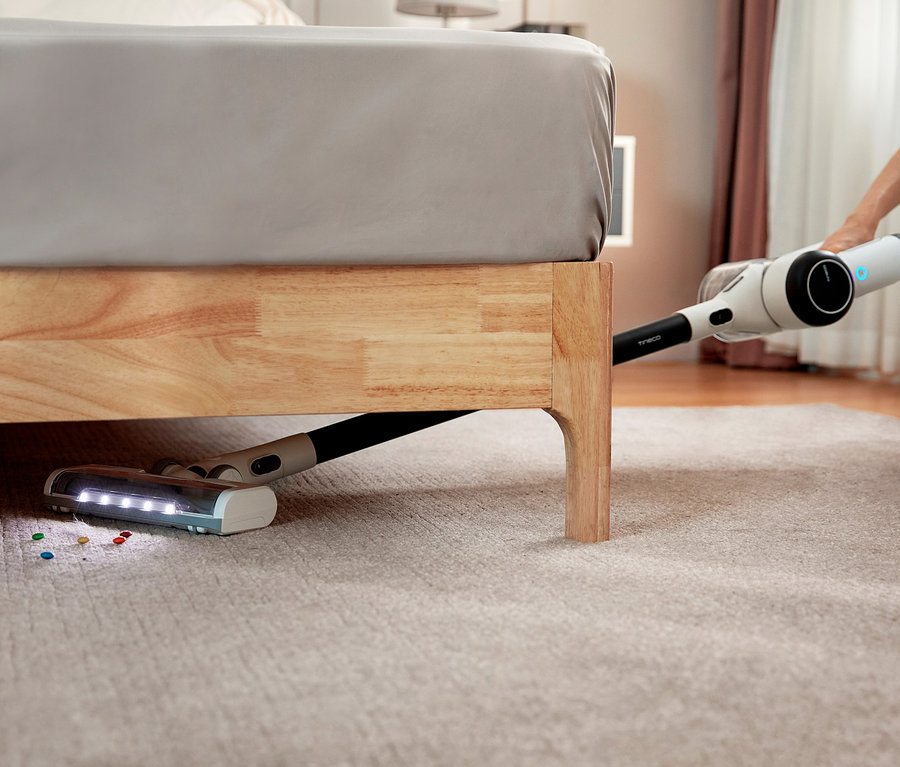 Frau saugt mit Tineco Pure One x Essentials Akkusauger unter dem Bett.