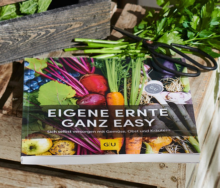 Eine Kiste mit Radieschen und Kohlrabi neben dem Buch »Eigene Ernte ganz easy«.