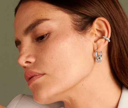 Frau sitzt und trägt einen Earcuff Sparkle Donut, einen Ring Sparkle Donut, Creolen Sparkle Donut und eine Kette Sparkle Donut.