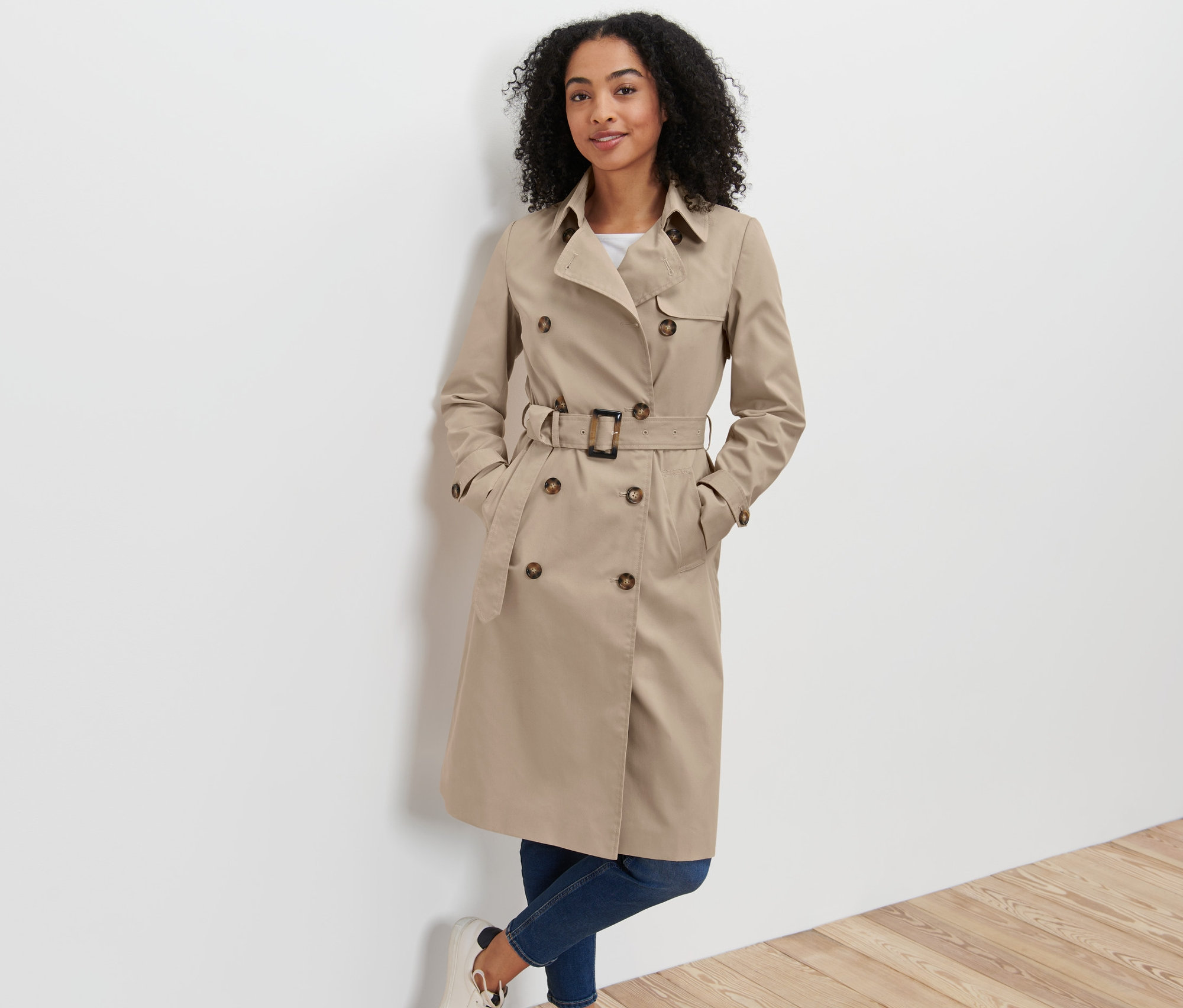 Frau posiert in beige Trenchcoat.