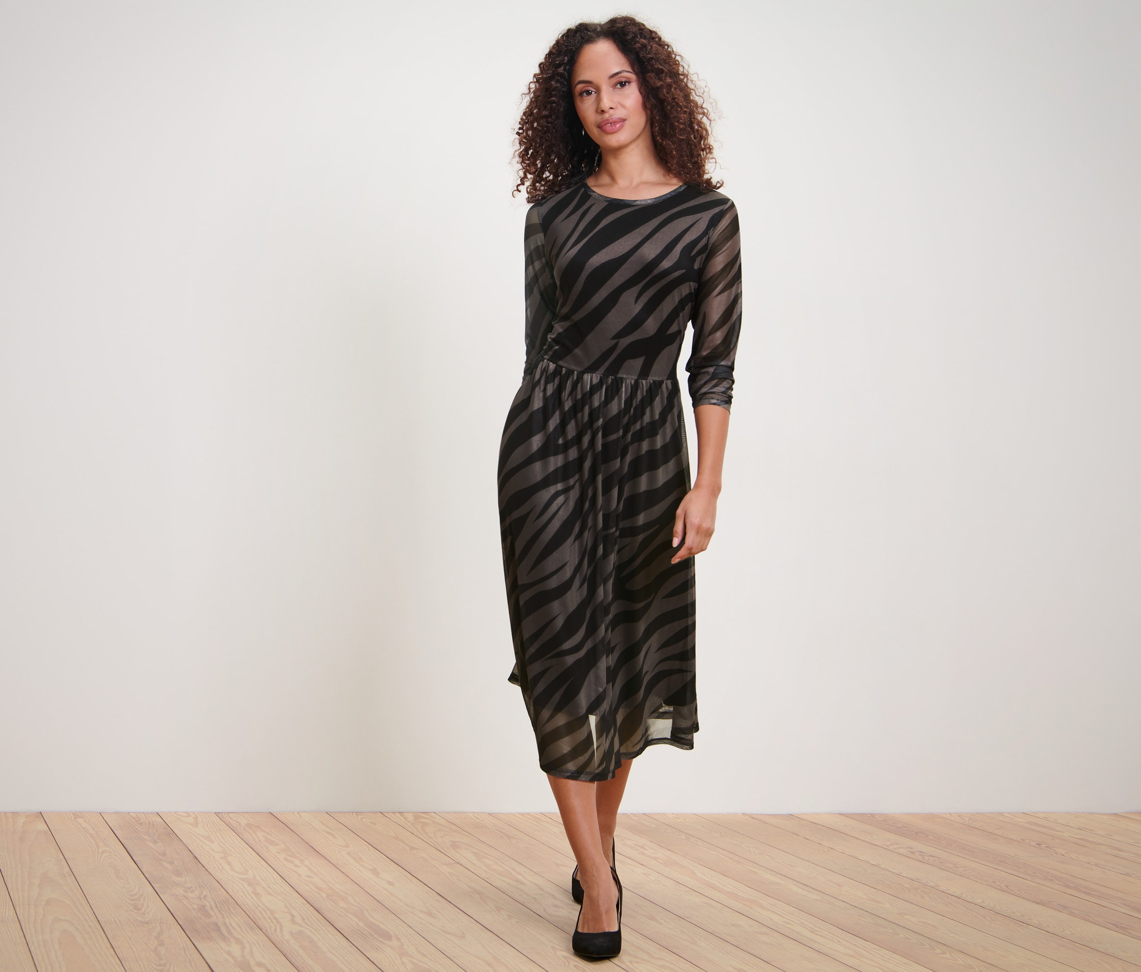 Frau posiert in einem bedruckten Mesh-Kleid.