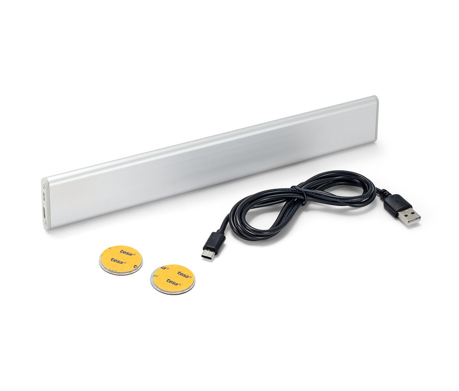 Eine LED-Akku-Multifunktionsleuchte, ein schwarzes Kabel und zwei Klebepads auf weißem Hintergrund.