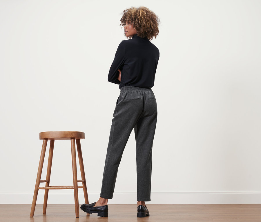 Frau mit verschränkten Armen, von hinten gesehen, trägt eine Joggpants.