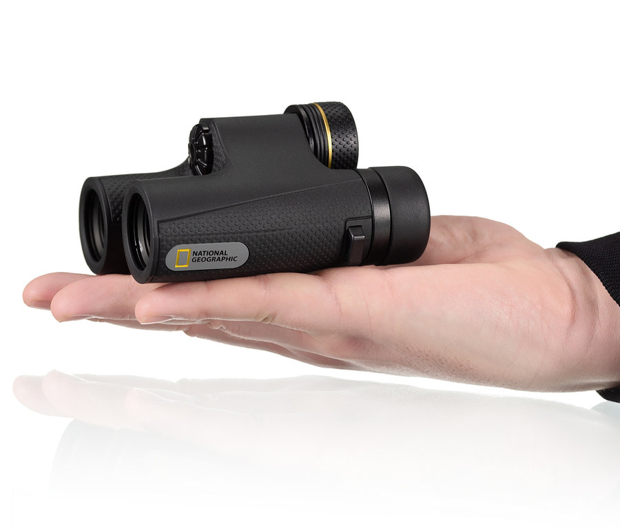 Eine Hand hält ein schwarzes NATIONAL GEOGRAPHIC 10x25-Taschenfernglas mit hochwertigen BaK-4-Prismen.