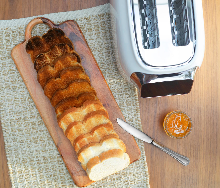 Toastscheiben auf einem Holzbrett neben einem Tineco Toaster »Toasty One«, einem Messer und einem Glas Marmelade.