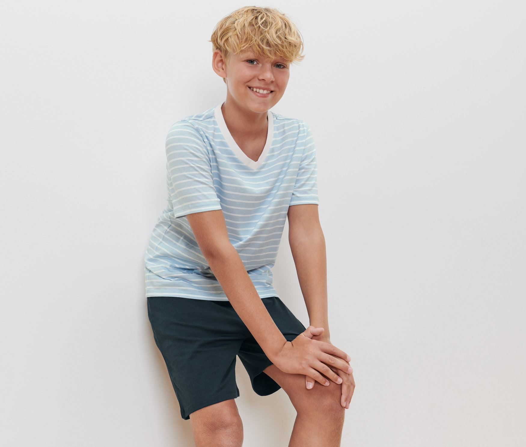 Ein Junge posiert in einem kurzen Kinder-Pyjama.