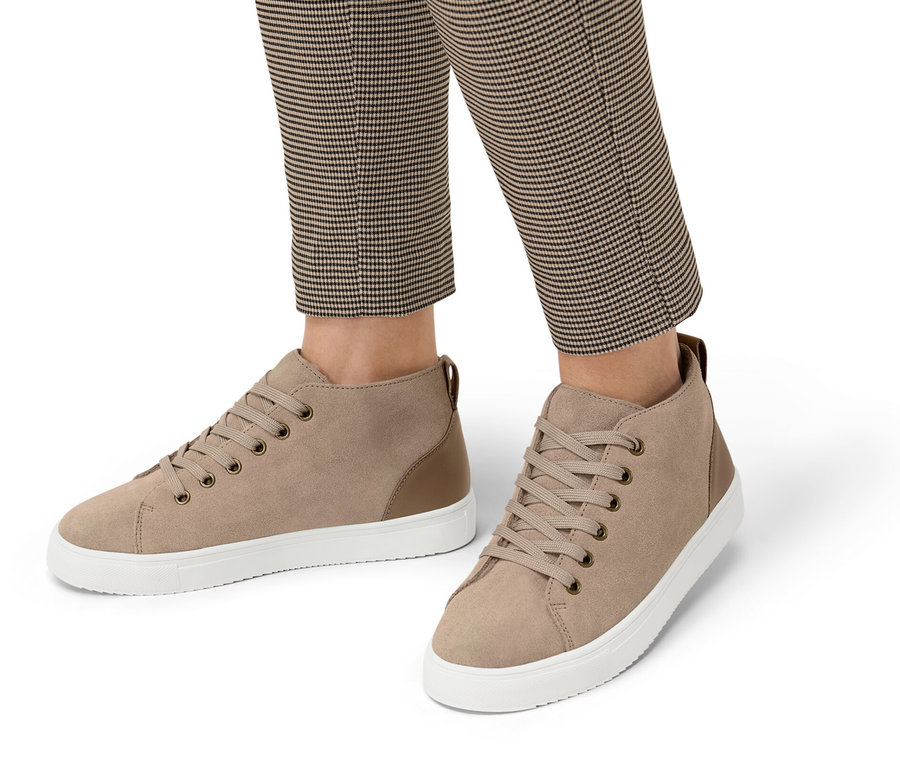 Beine einer Person in karierter Hose, die gefütterte Veloursleder-Sneaker trägt.