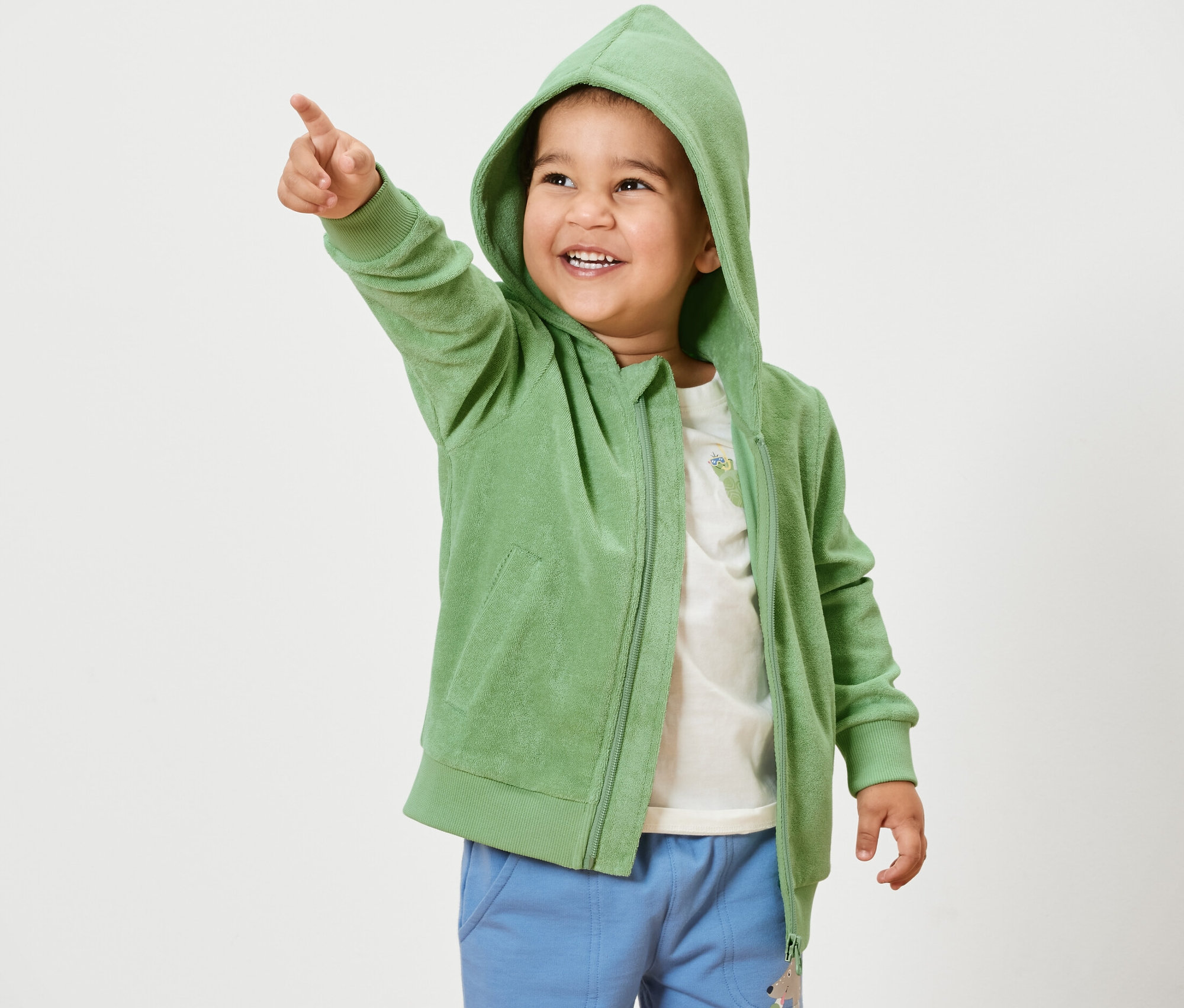 Junge zeigt in grüner Kinder-Frottier-Jacke mit dem Finger.