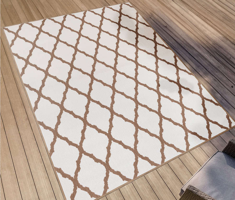 Ein brauner und weißer Outdoor-Wende-Teppich "Rhombus" liegt auf einem Holzdeck neben Korbmöbeln.