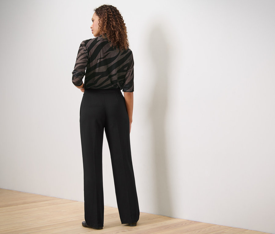 Frau von hinten trägt eine Jerseyhose mit Biese und ein Oberteil mit Tiermuster.