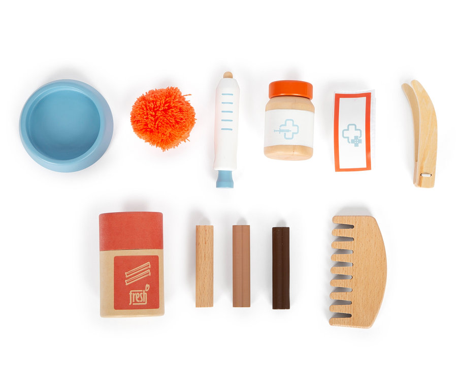 Eine leere blaue Schüssel, ein orangefarbener Bommel, eine Spritze, eine Medikamentenflasche, ein Verband, eine Pinzette, eine Schachtel, 3 Stäbchen und ein Kamm auf weißem Hintergrund.