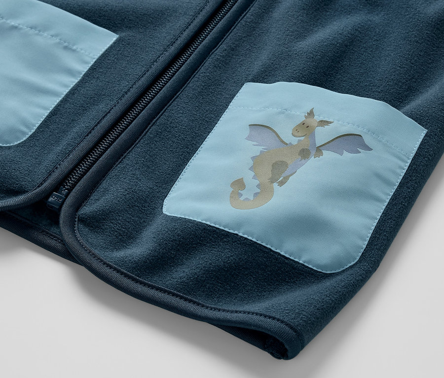 Detailaufnahme einer Kinder-Fleeceweste, Drache, mit blauem Drachenflicken auf der Tasche.
