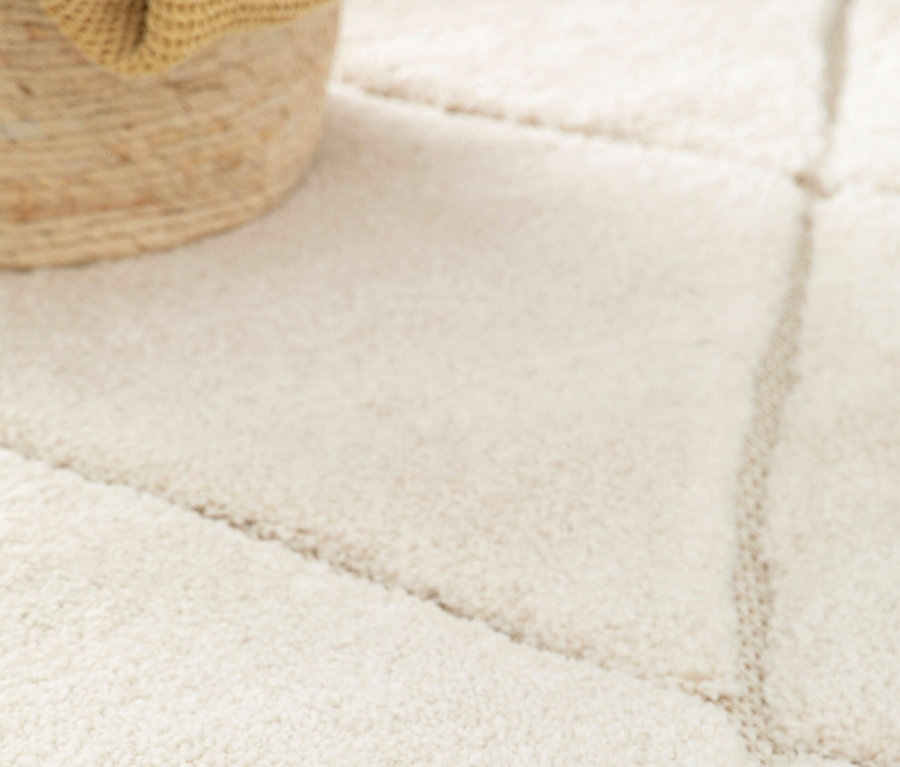 Detailansicht eines beigen Teppichs »NATIVO Boho Lines« mit geometrischem Muster, daneben ein Korb.