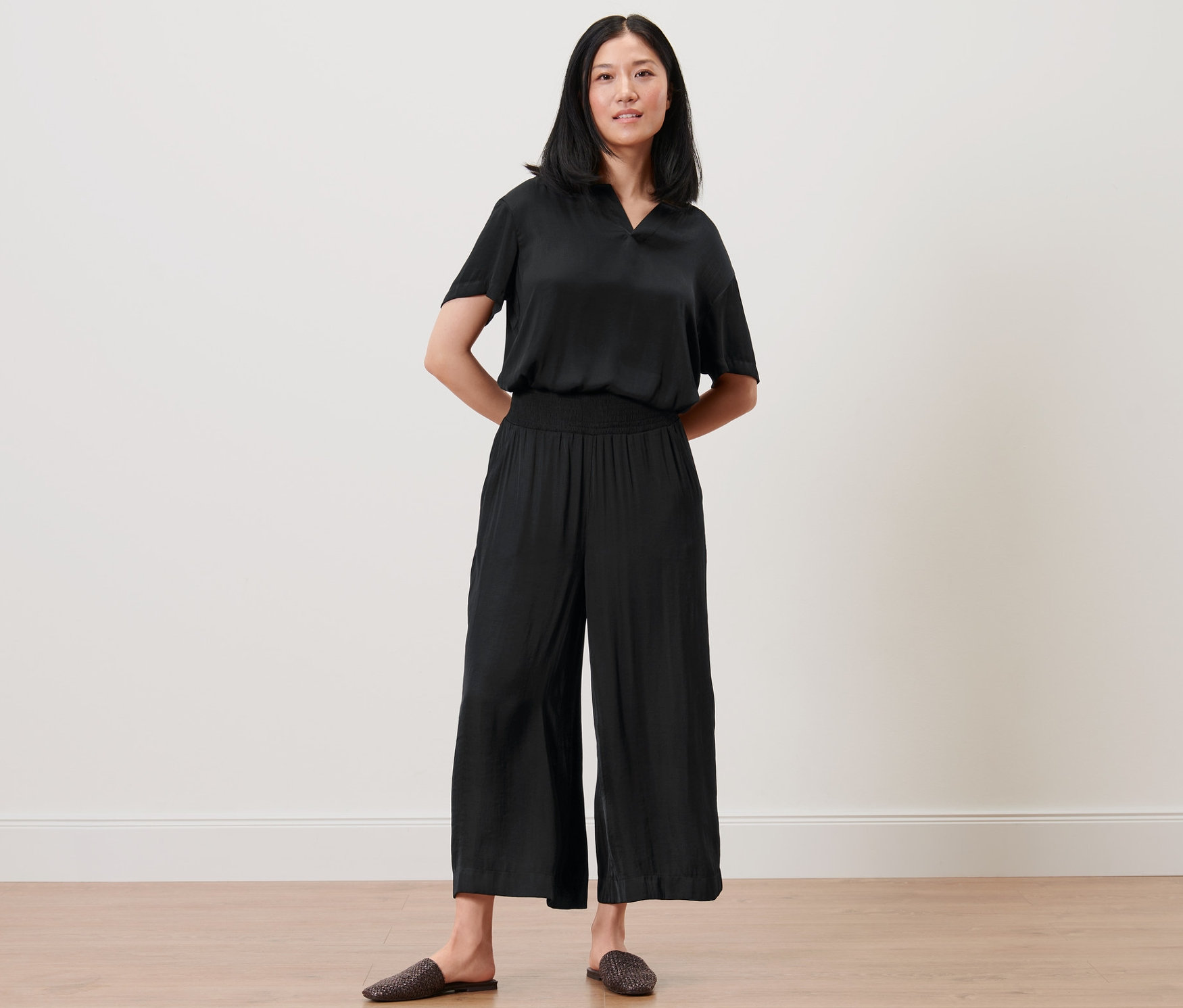 Frau posiert in schwarzen Satin-Culottes und Oberteil.