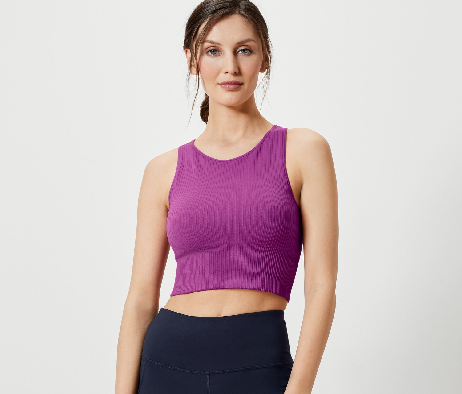 Frau posiert in Seamless-Sport-Bralette und marineblauen Leggings.