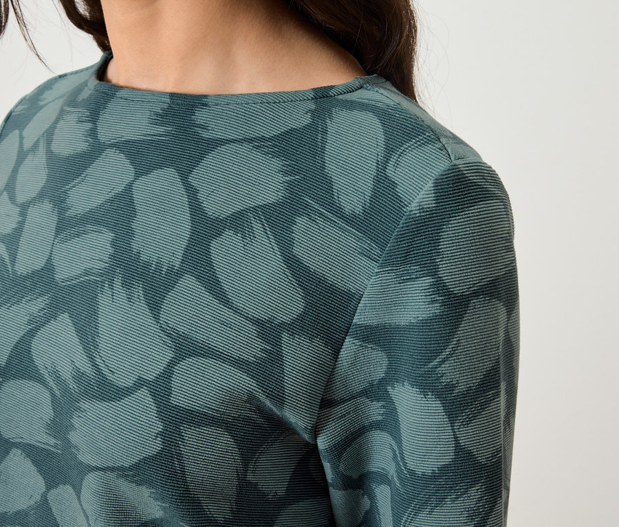 Detailaufnahme eines Damenkleides mit langen Ärmeln und abstraktem Muster.