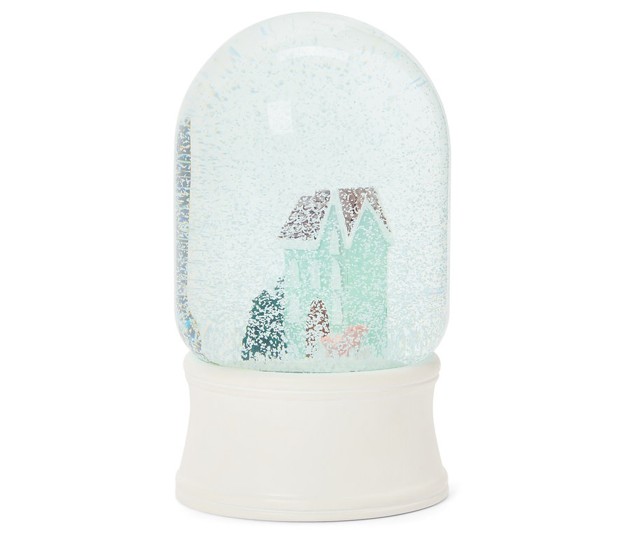 Schneekugel mit Hausmotiv auf weißem Sockel.