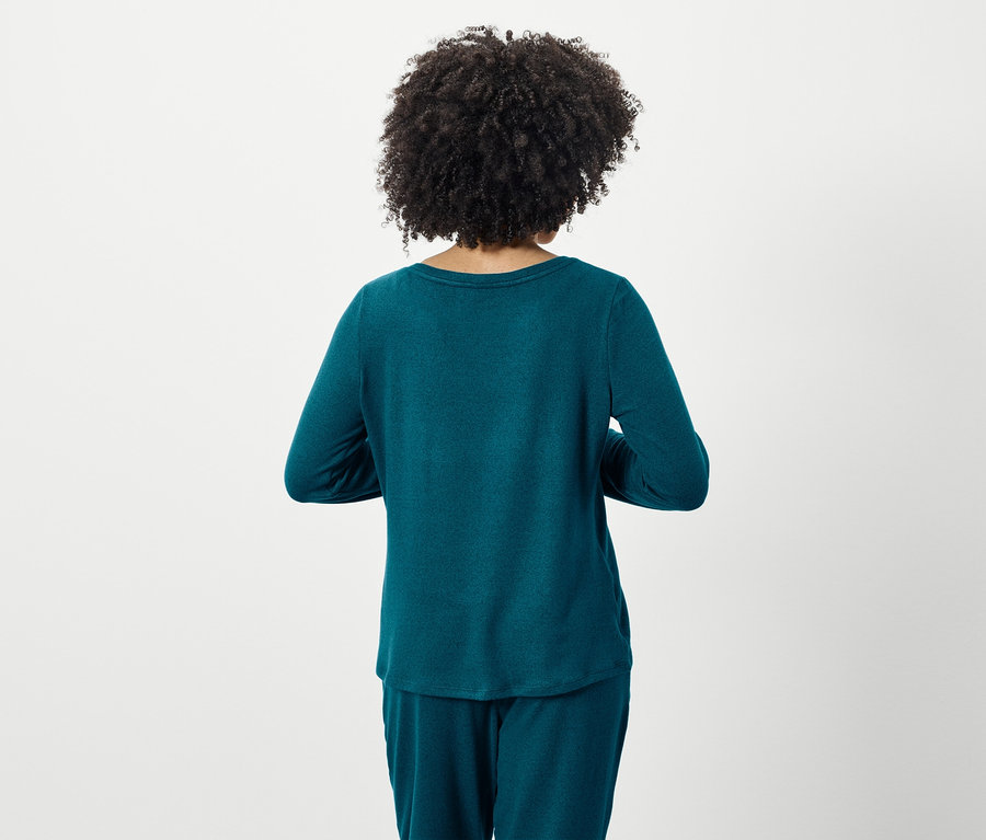 Rückansicht einer Frau mit Afro-Frisur, die einen türkisfarbenen langärmeligen Pyjama und eine Hose trägt.