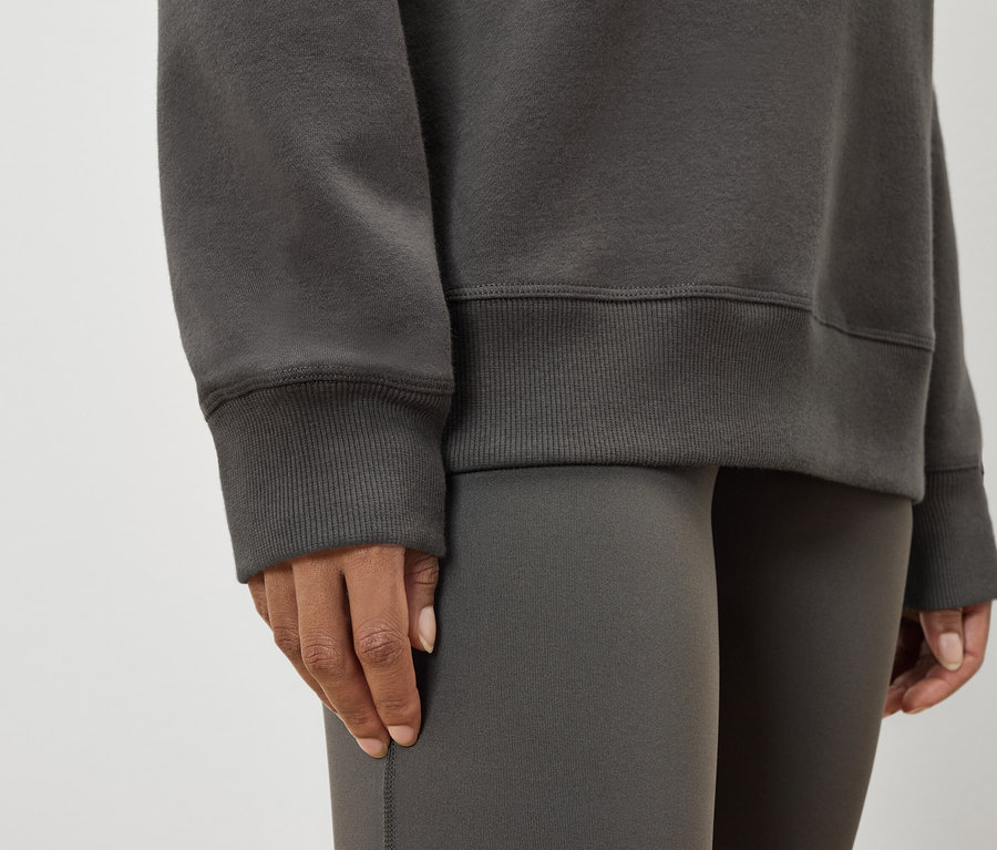 Detailaufnahme einer Frau, die einen grauen Pullover und Leggings trägt.