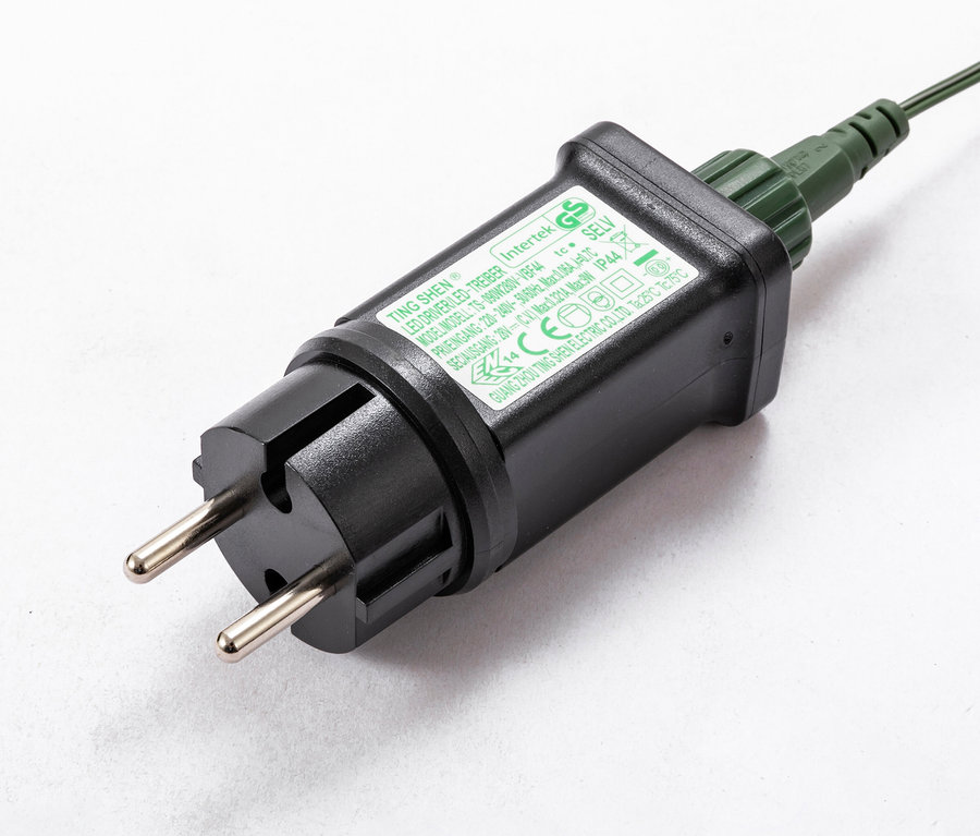 Detailaufnahme eines schwarzen Adapters mit Stecker und grünem Kabel.