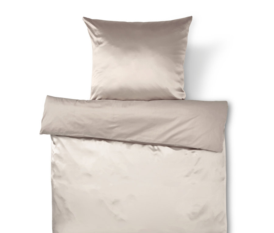Beige Satin-Bettwäsche mit Kissen und Bettdecke.