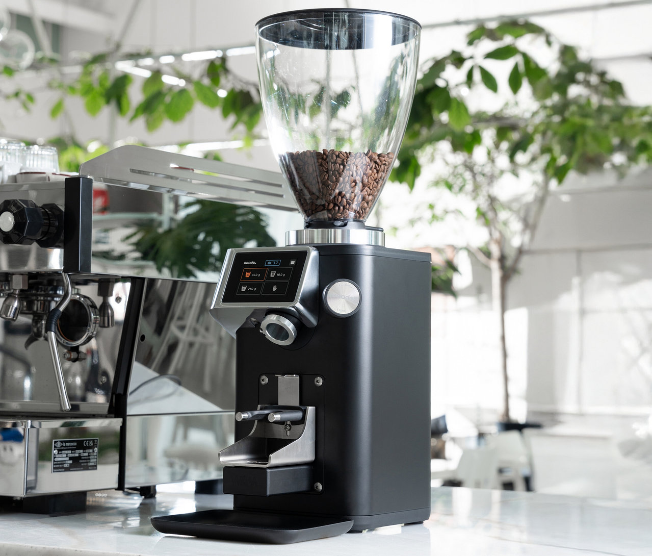 Eine schwarze Kaffeemühle steht neben einer Kaffeemaschine.