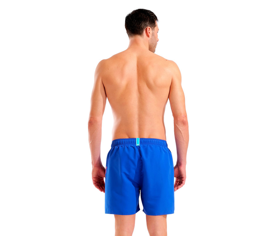 Rückenansicht eines Mannes mit blauen Badeshorts vor weißem Hintergrund.