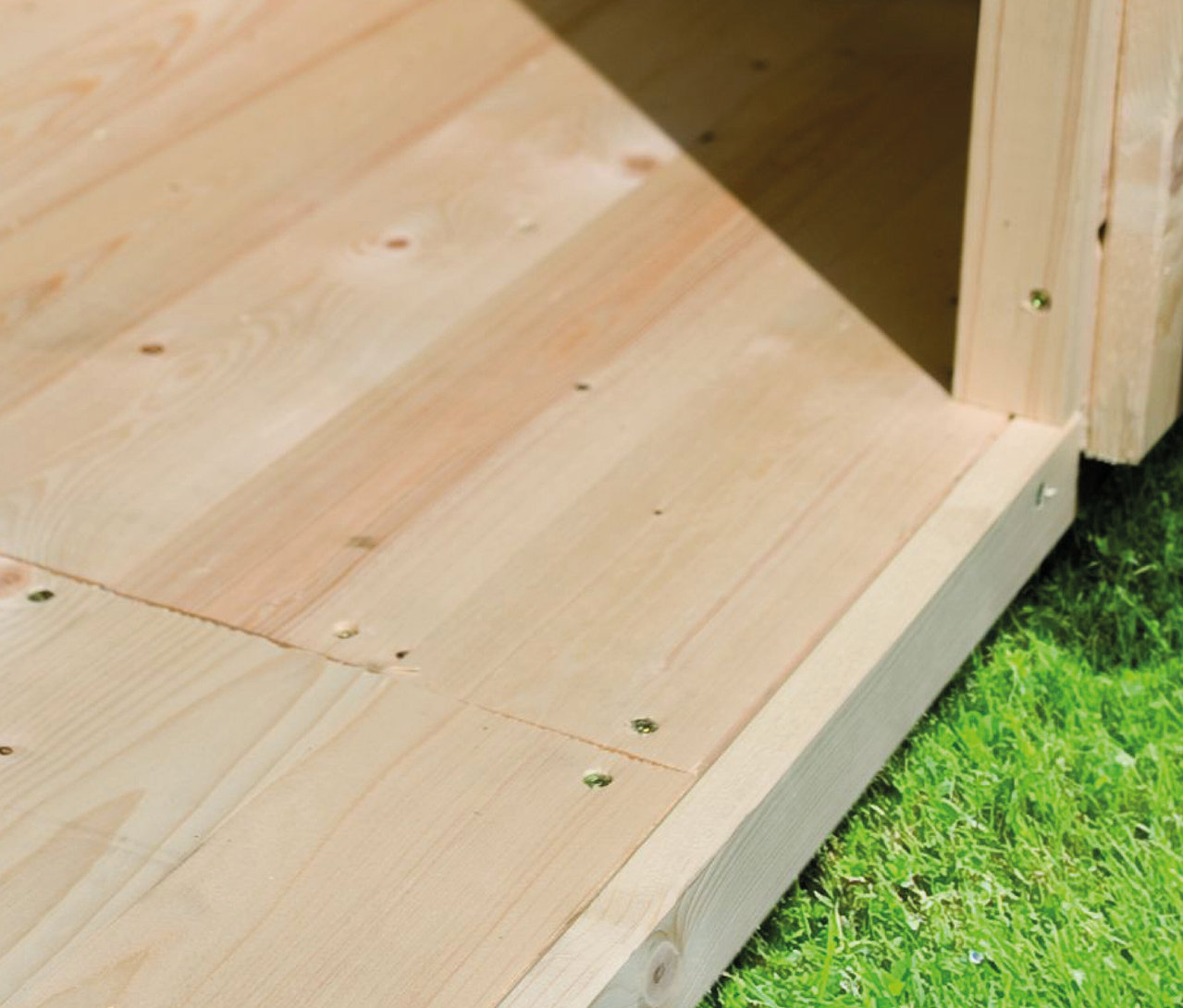 Detailansicht vom Boden und Eingangsbereich eines Karibu Modernes Gartenhaus mit Schiebetür »Noelia 5«, 38 mm, auf Rasen.