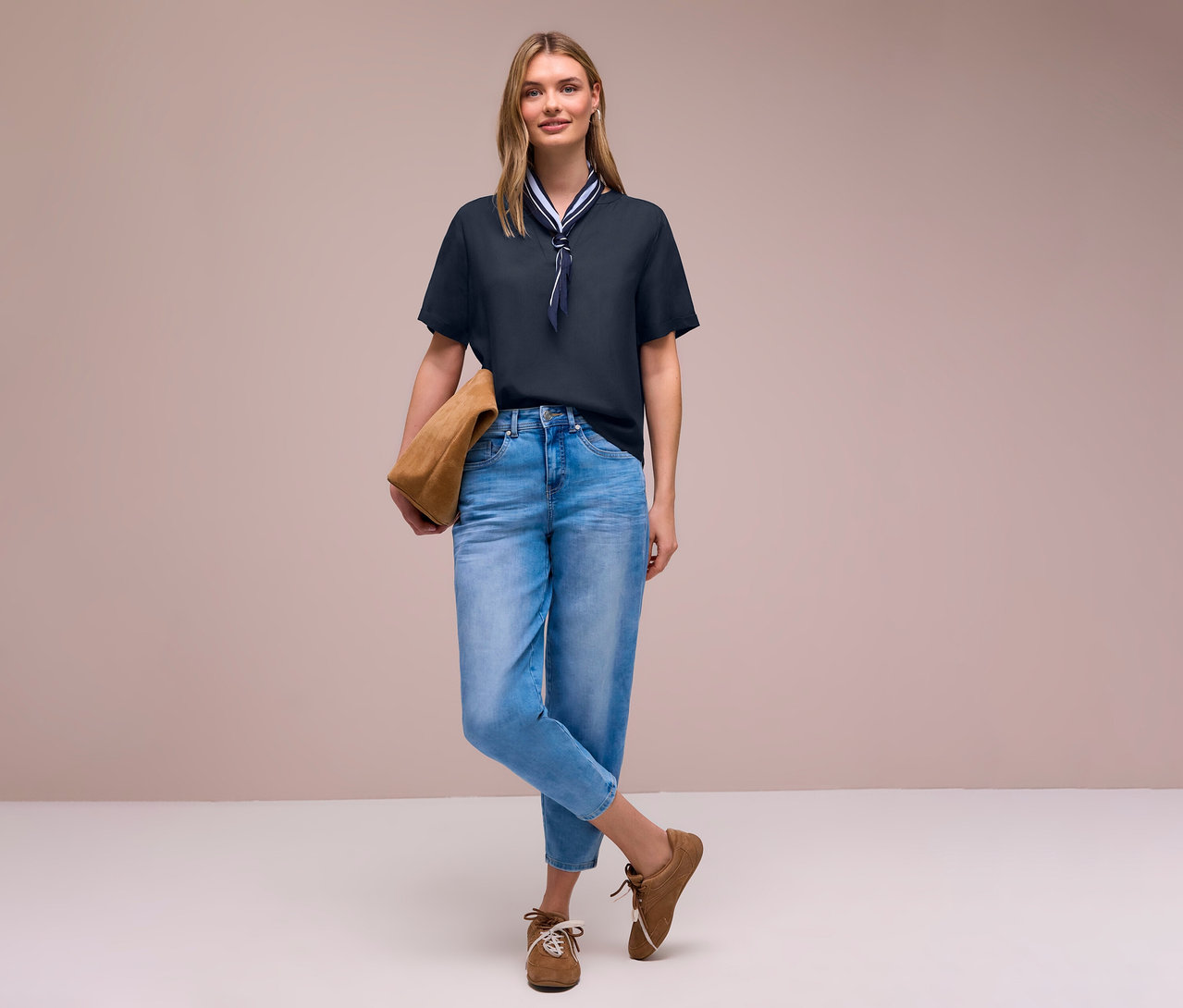 Frau in Jeans und braunen Schuhen mit Tasche, trägt eine Street One Webbluse mit Halstuch.