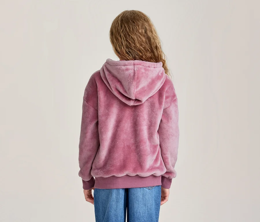Person von hinten gesehen, trägt einen rosa flauschigen Hoodie und blaue Jeans.