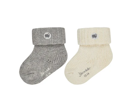Zwei gestrickte Babysocken, eine graue und eine cremefarbene, mit umgeschlagenen Bündchen. Jedes Bündchen hat einen runden Aufnäher mit einem Schaf-Logo, und "Sterntaler 13-14" ist auf dem Fußteil jeder Socke aufgedruckt.