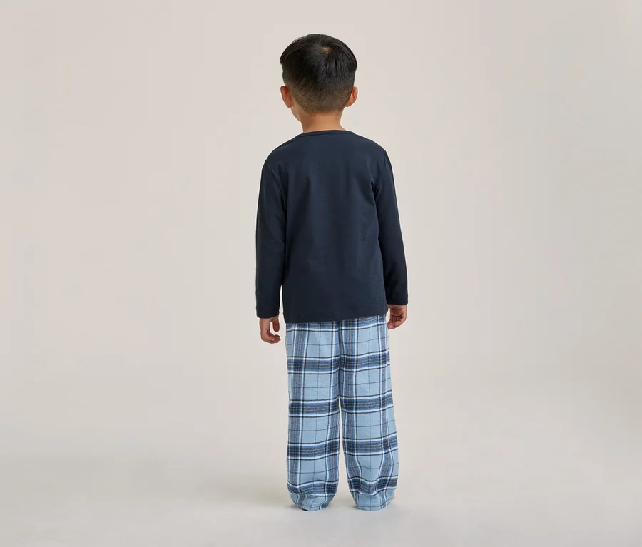 Ein Kind von hinten gesehen, das ein dunkelblaues Langarmshirt und eine blau karierte Pyjamahose trägt.