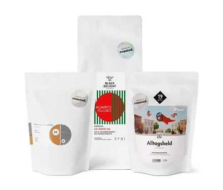 Vier Packungen Kaffeebohnen unterschiedlicher Röstungen stehen nebeneinander.