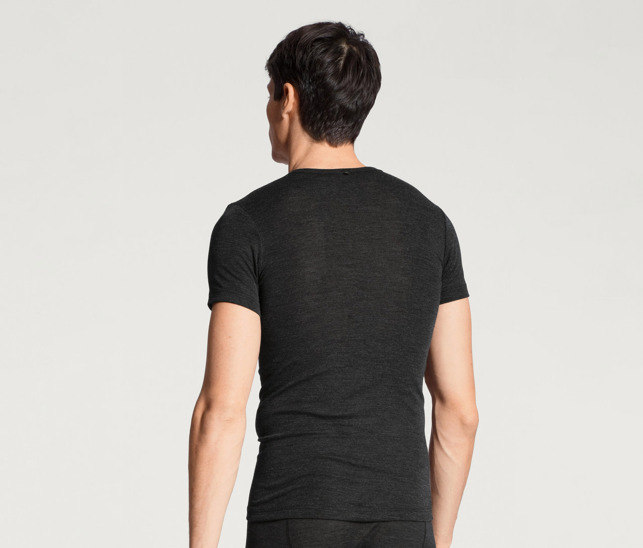 Mann von hinten, der ein dunkelgraues Kurzarm-T-Shirt und eine passende Unterhose trägt und nach rechts blickt.