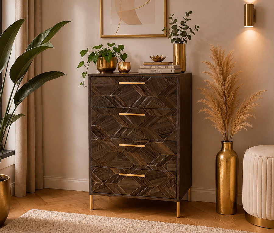 Dunkle Holzkommode mit geometrischem Muster, goldenen Griffen und Beinen, dekoriert mit Pflanzen, Büchern und Golddekor. Links steht eine große Pflanze, rechts eine hohe Vase mit Pampasgras und ein runder Hocker. Eine goldene Wandleuchte und gerahmte Kunst vervollständigen die Szene.