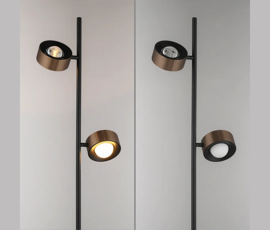 Stehlampe mit schwarzem Ständer und zwei runden, bronzefarbenen Leuchten. Links leuchtet die untere Leuchte warmgelb, die obere ist aus. Rechts leuchtet die obere Leuchte kaltweiß, die untere ist aus.
