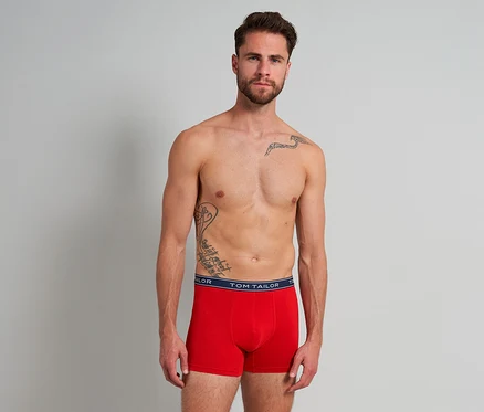 Ein oberkörperfreier Mann mit Bart und Tattoos trägt rote Tom Tailor Buffer Slipboxer mit marineblauem Bund.