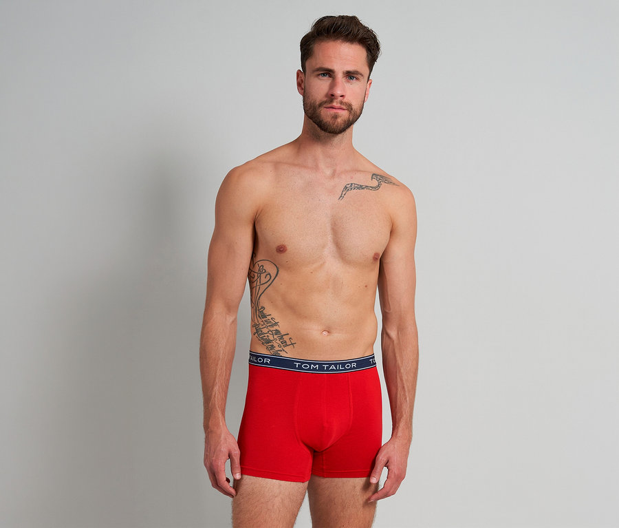 Ein oberkörperfreier Mann mit Bart und Tattoos trägt rote Tom Tailor Buffer Slipboxer mit marineblauem Bund.