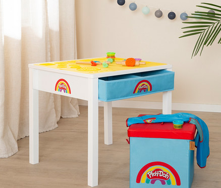 Ein weißer Spieltisch mit gelber Oberfläche und blauer Schublade, verziert mit dem Play-Doh-Logo, neben einer blauen Aufbewahrungsbox mit rotem Deckel.