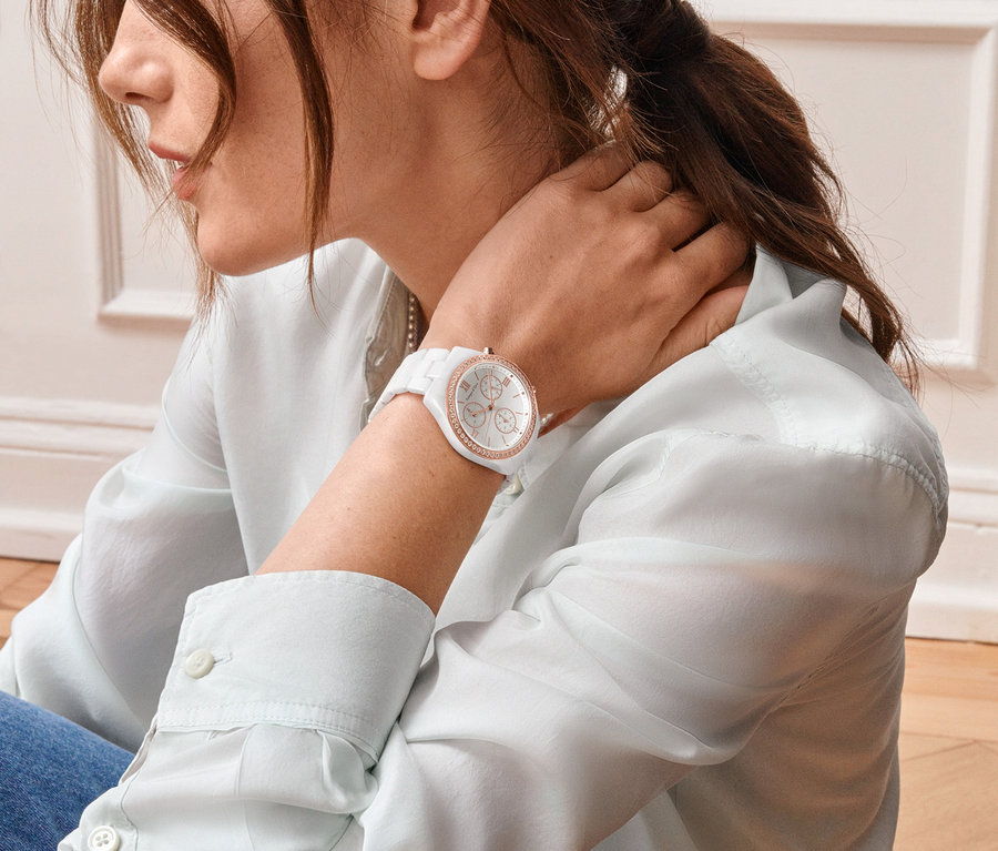 Frau berührt ihren Hals und trägt eine Keramik-Chronograph mit Zirkonia am Handgelenk.