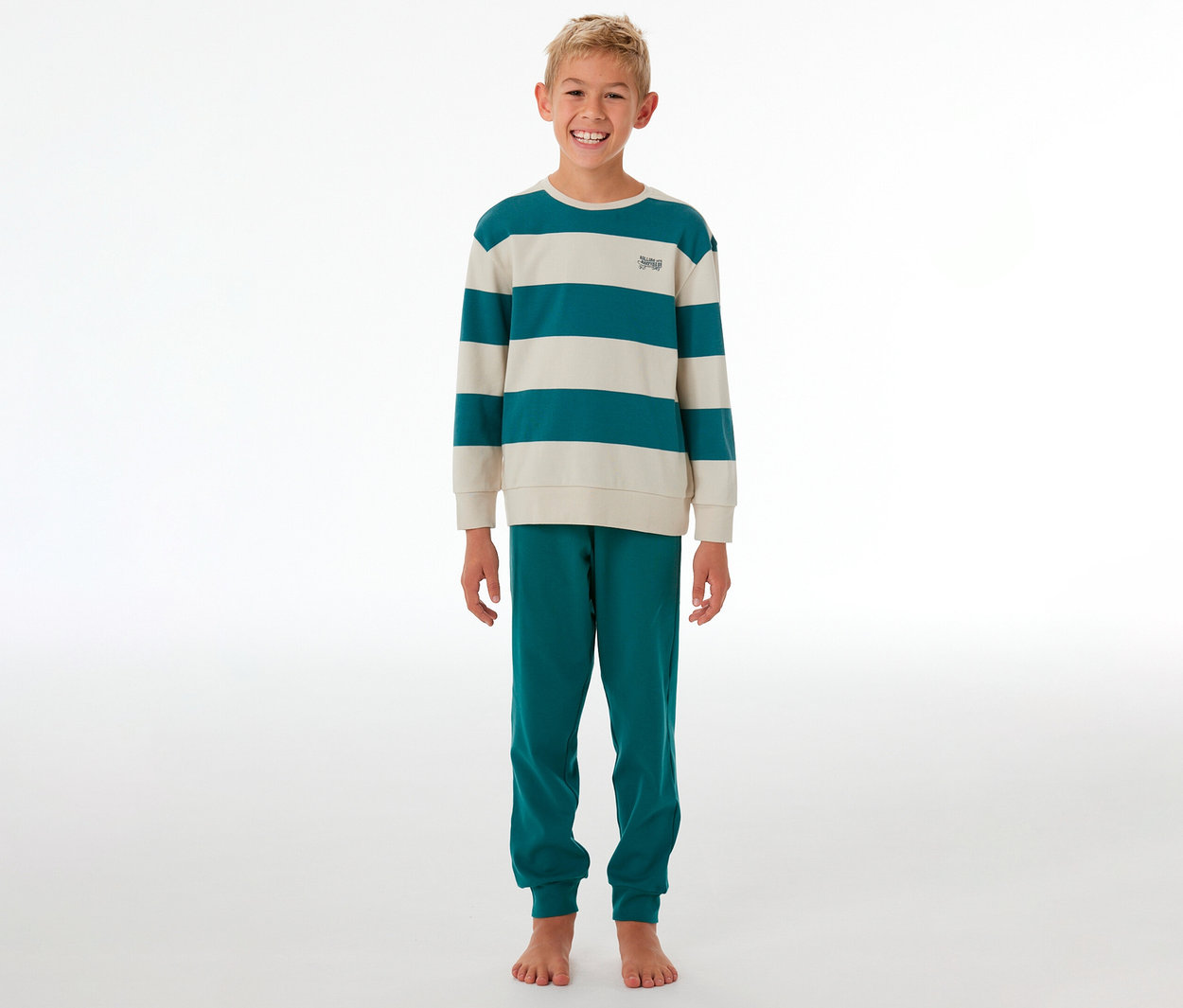 Lächelnder Junge steht in einem gestreiften SCHIESSER Kinder-Interlock-Pyjama in Türkis und Beige.