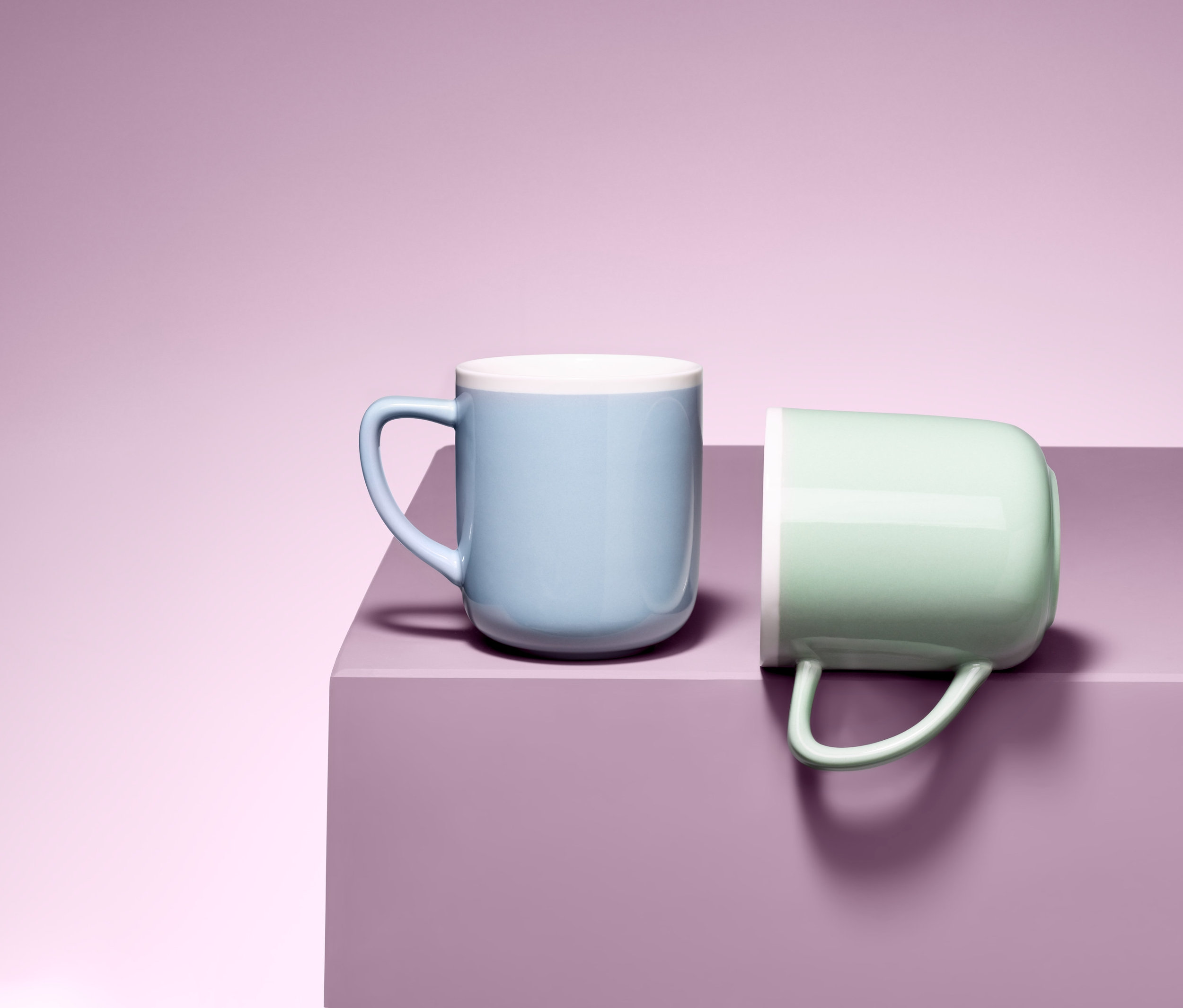 Zwei Becher auf einer lila Oberfläche. Einer hellblau, der andere hellgrün.