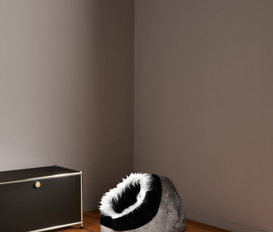 In der Ecke des Raumes steht eine Karlie-Katzen-Kuschelhöhle neben einem schwarzen Schrank.