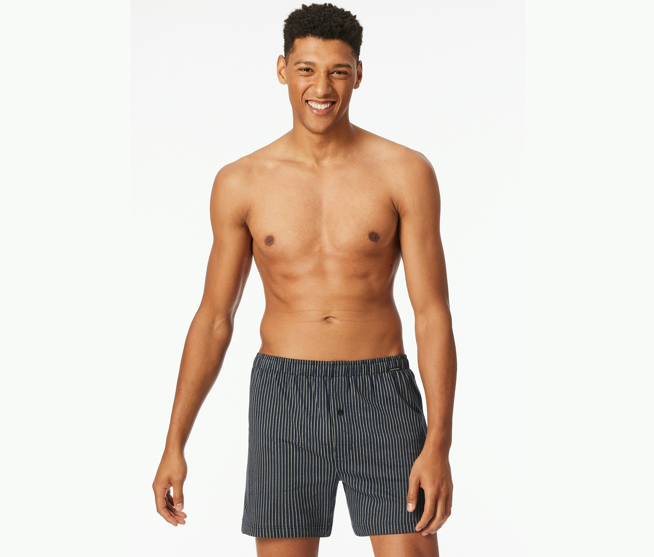 Lächelnder Mann mit freiem Oberkörper trägt gestreifte Boxershorts.