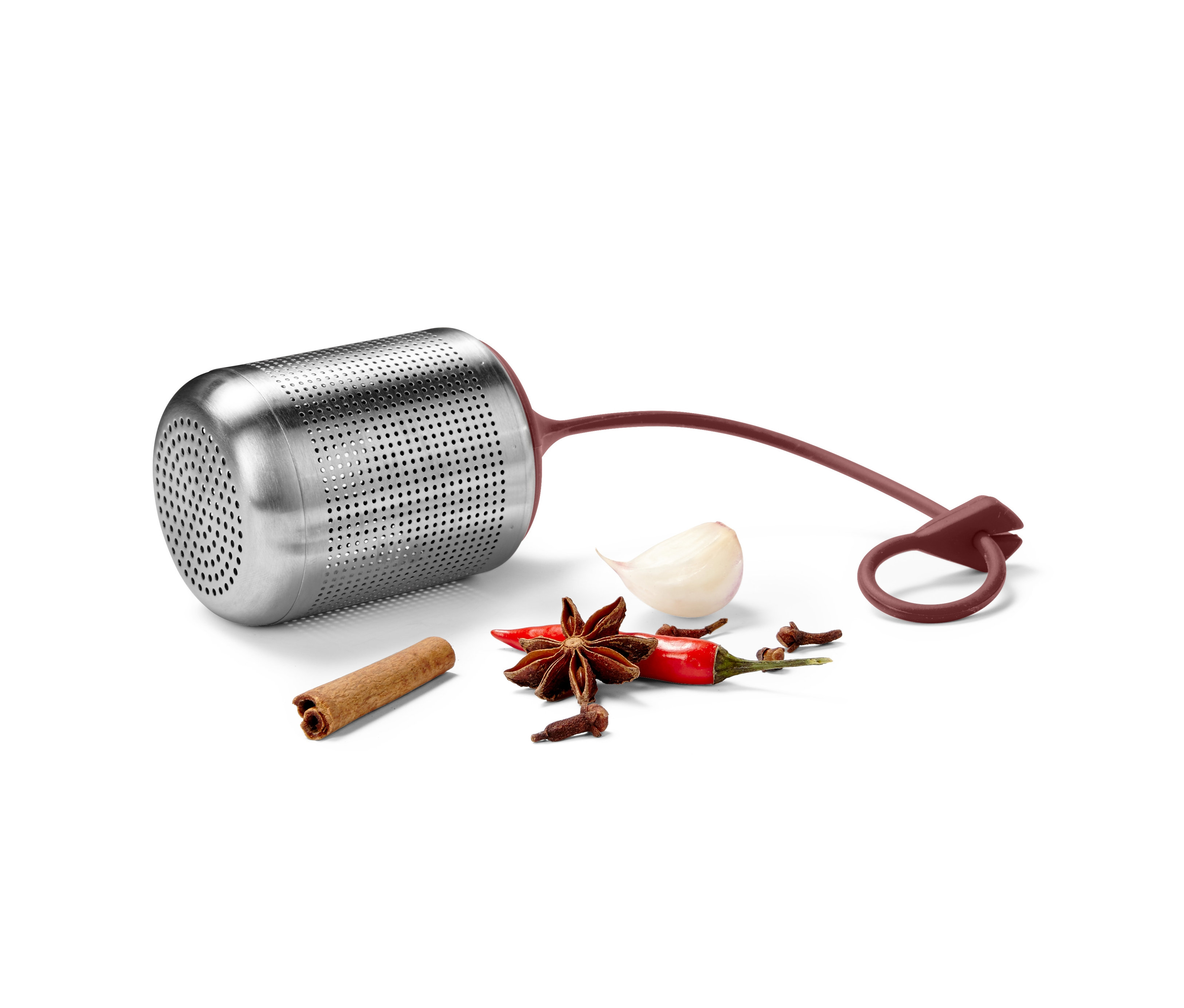 Ein Gewürzsieb aus Metall liegt auf einer weißen Oberfläche neben Gewürzen.